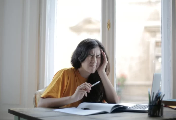 a female student with head and side jaw ache holding pen